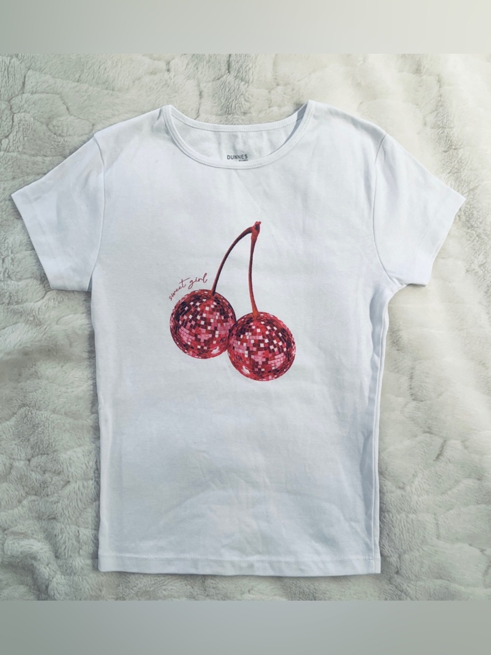 T-shirt featuring a red disco ball cherry graphic and the phrase "sweet girl".S
